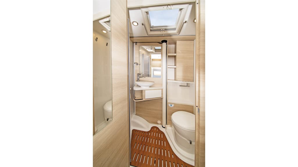 Das Bad mit großem Dachfenster, Drehtoilette, Acrylglas-Falttüren und zum Duschen wegschwenkbarem Waschtisch.