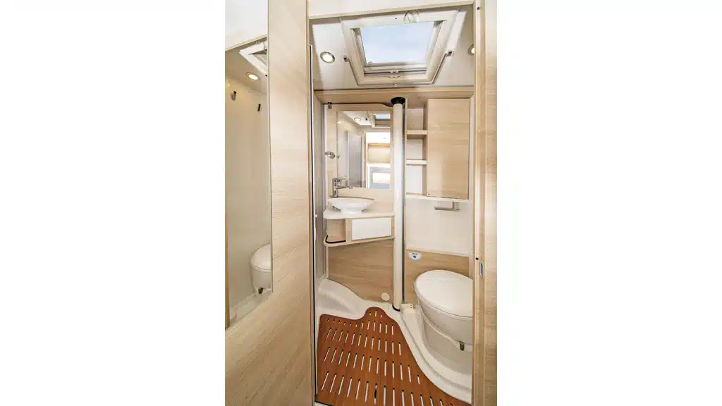 Das Bad mit großem Dachfenster, Drehtoilette, Acrylglas-Falttüren und zum Duschen wegschwenkbarem Waschtisch.