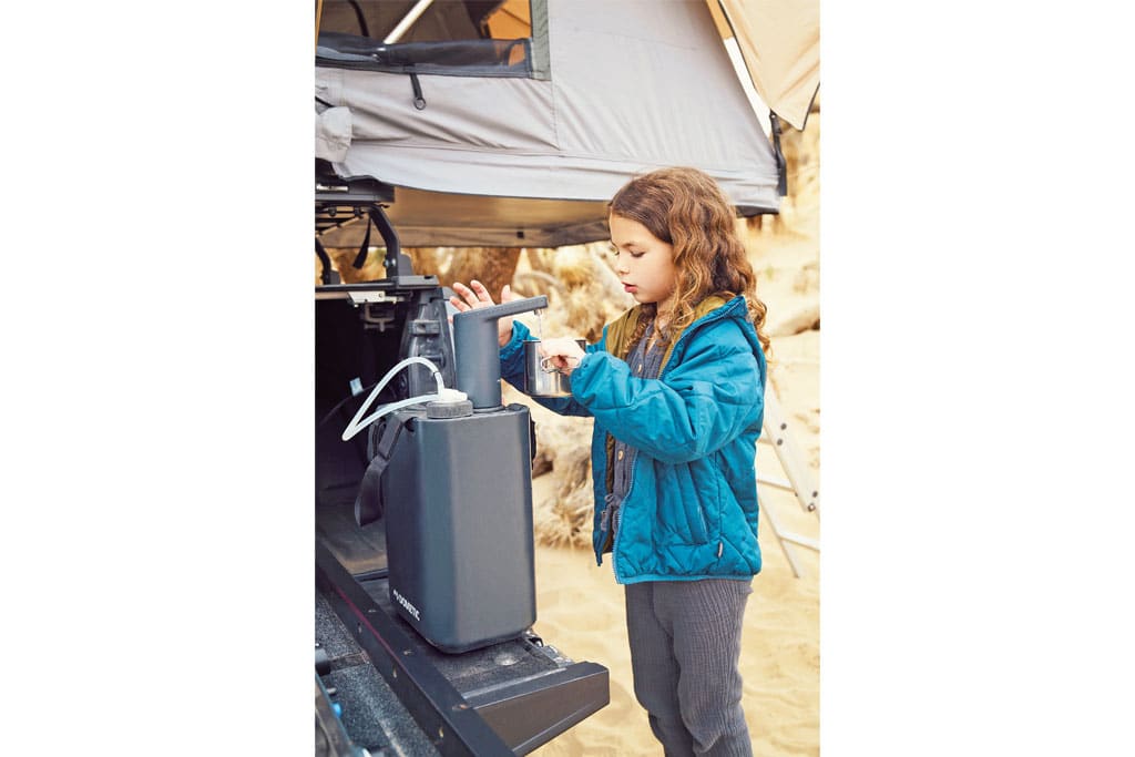 Kind zapft Frischwasser aus dem Dometic Hydration Kit in eine Tasse
