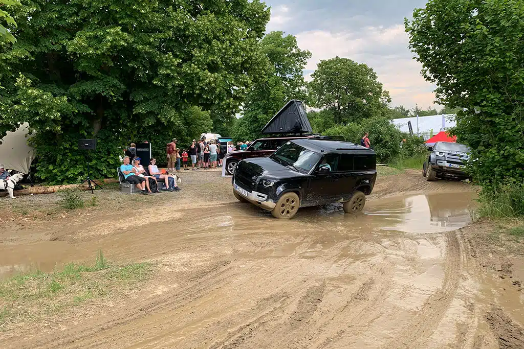 Schwarzer Land Rover durchquert matschig-nassen Weg beim Land Rover Parcours