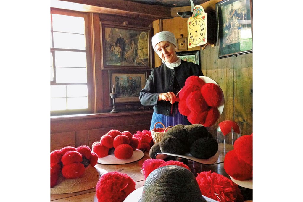 Hutmacherin beim fertigen der traditionellen roten Bollenhüte im Freilichtmuseum