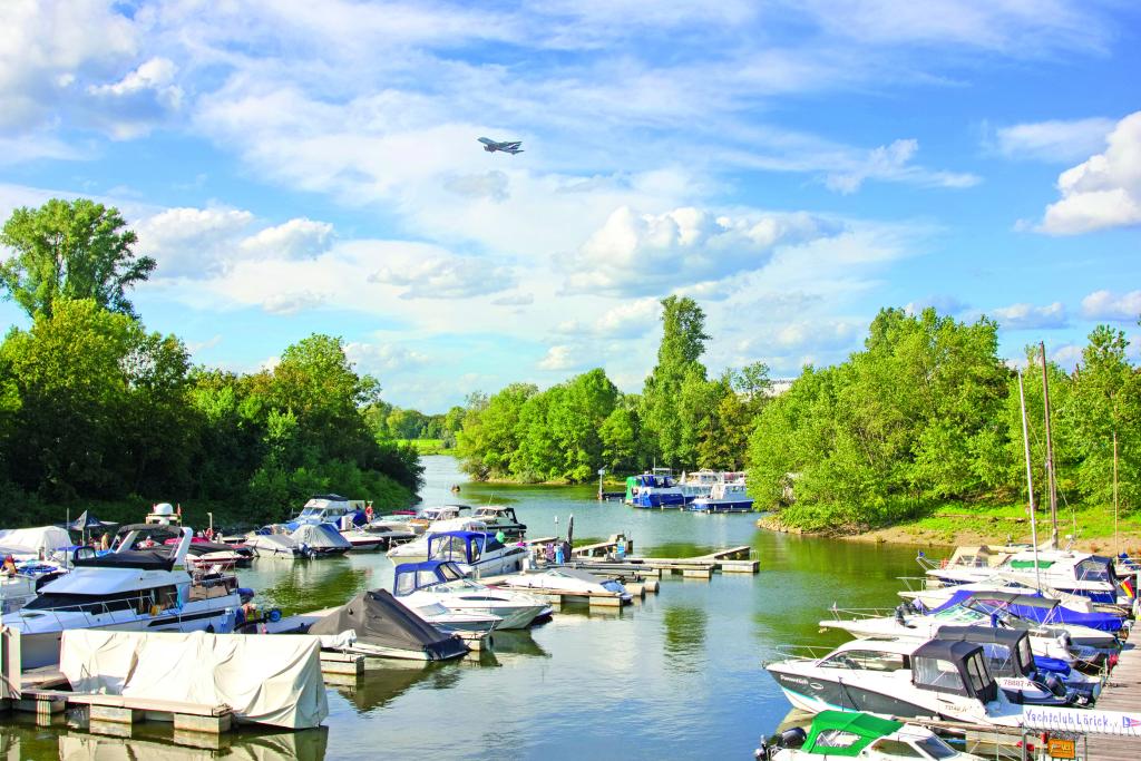 Kleine Boote im Fluss, am Flussufer grüne Laubbäume