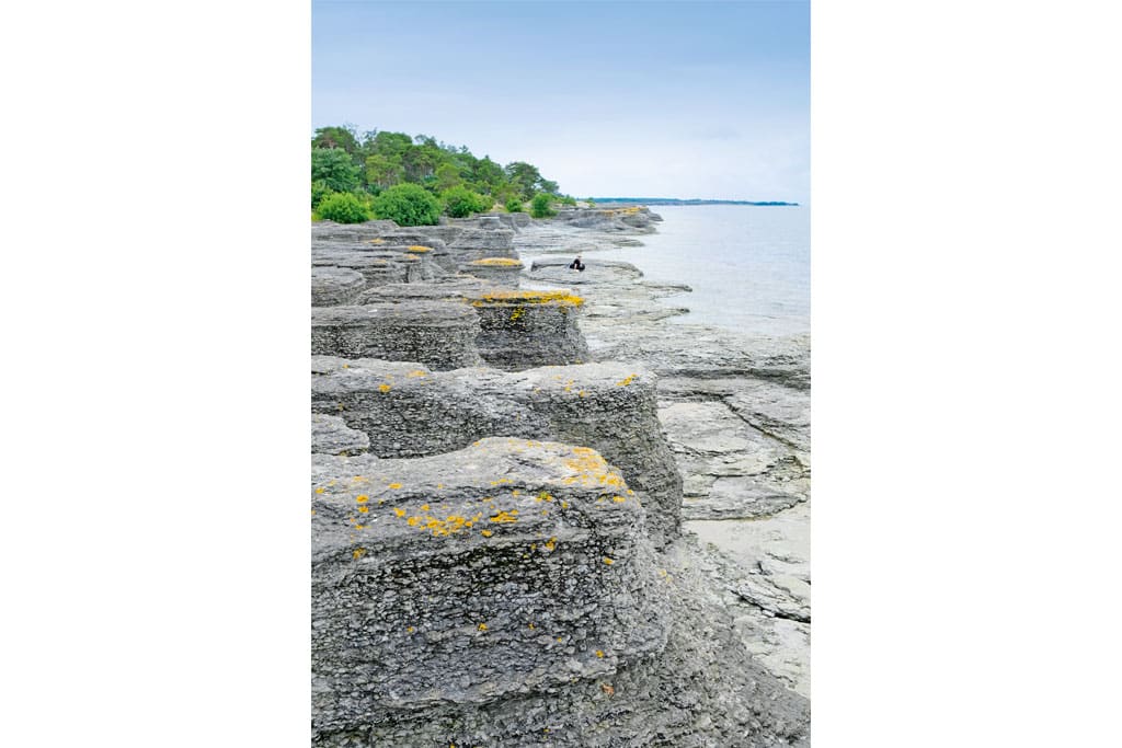 Eine Person sitzt an einer felsigen Küste