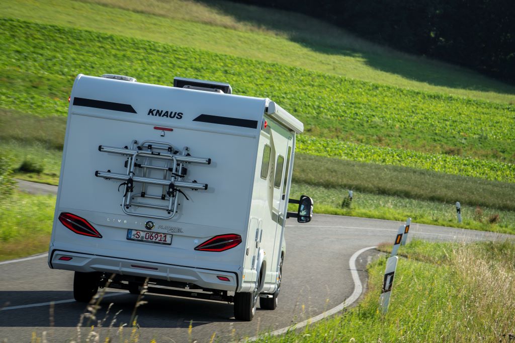 Heckansicht eines weißen Wohnmobils auf einer kurvigen Landstraße