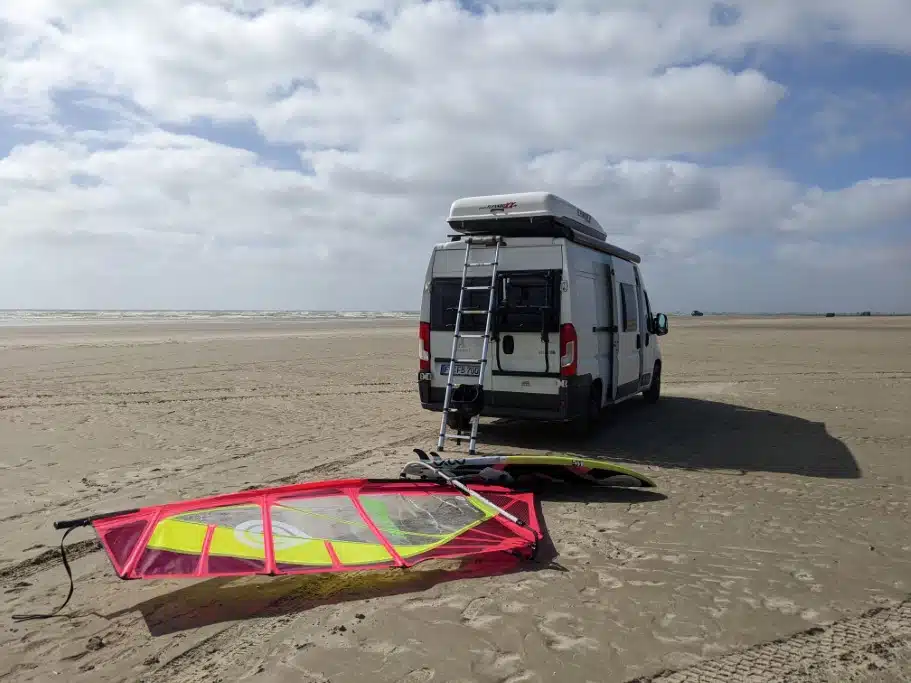 Camper mit Dachbox und Windsurfbrett