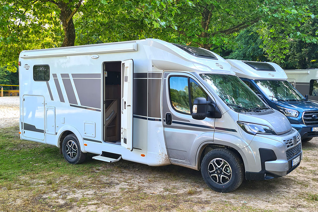 Carado T328 Pro+: Teilintegriertes Wohnmobil von außen unter Bäumen