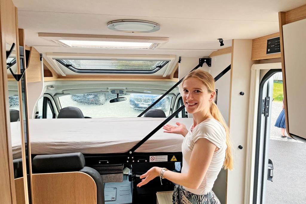 Redakteurin präsentiert das herabgelassene Hubbett im Wohnmobil