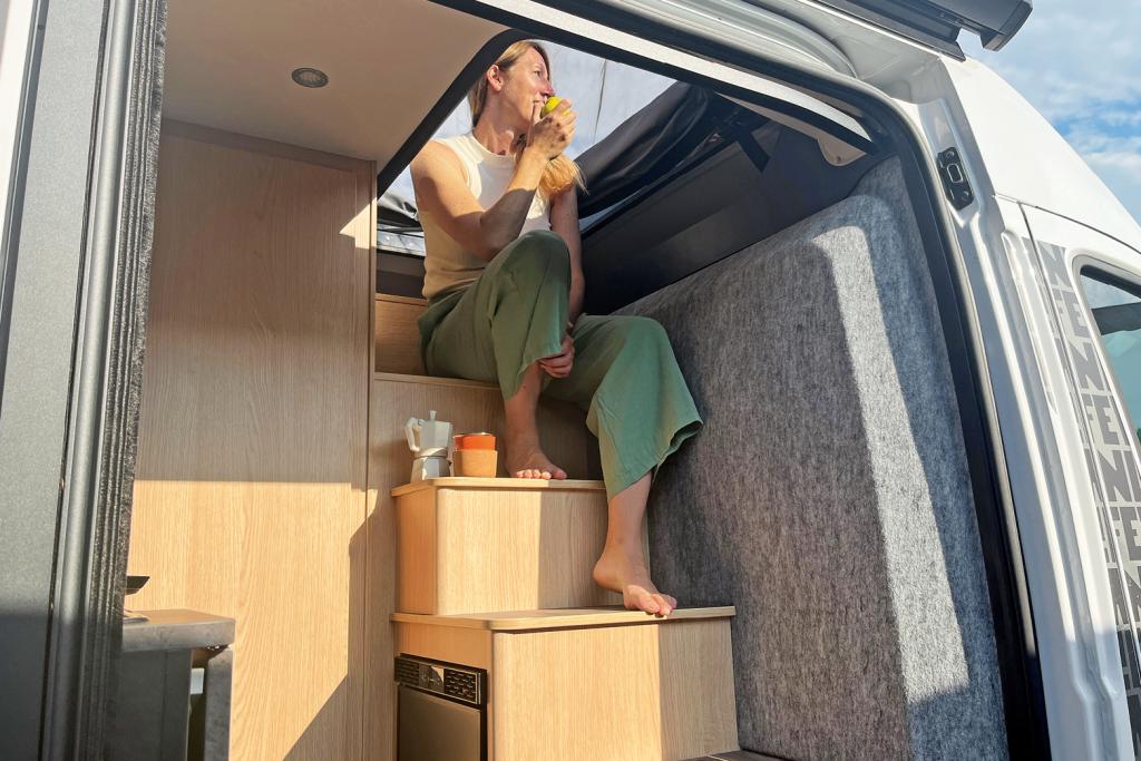 Redakteurin sitzt auf der festen Treppe hinter den Fahrersitzen im Campervan