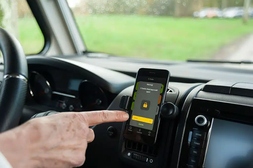 Mann tippt auf App im Smartphone vom Steuer im Auto aus