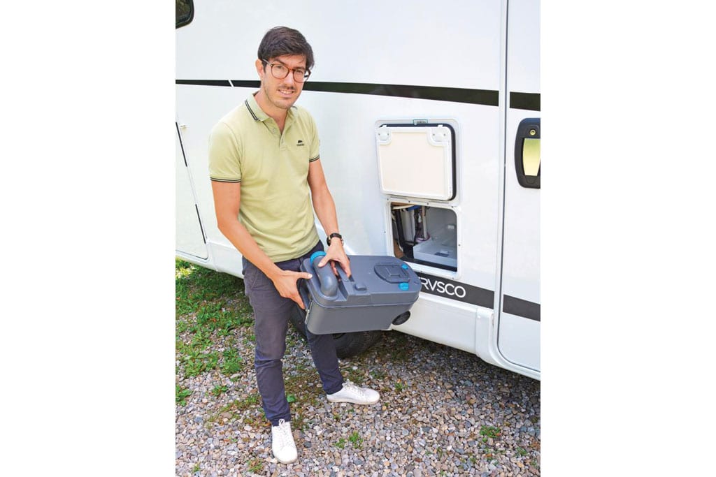 Redakteur mit Behälter einer Campingtoilette vor dem WC-Schacht des Wohnmobils