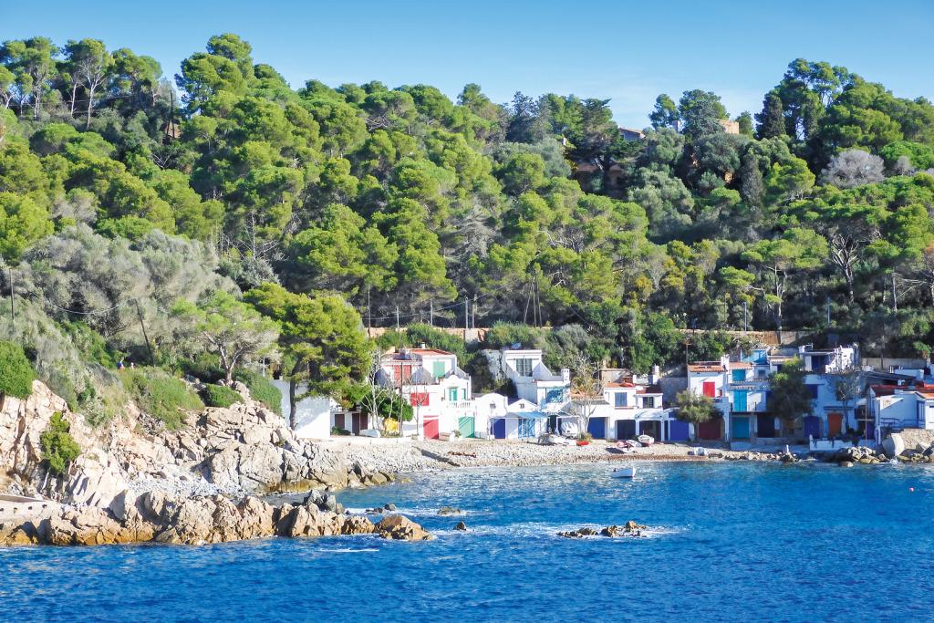 Bucht mit felsiger Küste und einigen weißen Häuschen mit bunten Türen