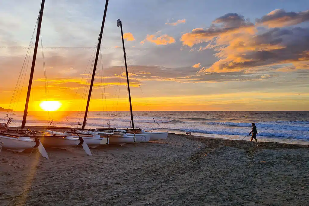 Sonnenaufgang am Meer, am Strand liegen ein paar kleine Boote