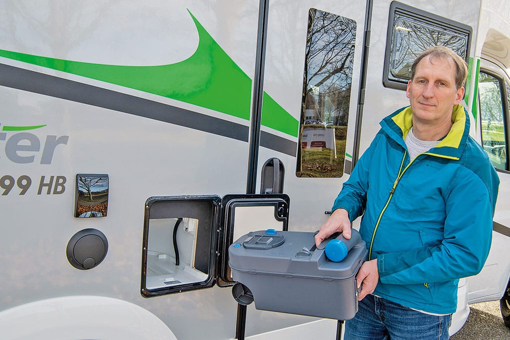 Redakteur hebt Chemietoilette aus dem Toilettenschacht des Wohnmobils